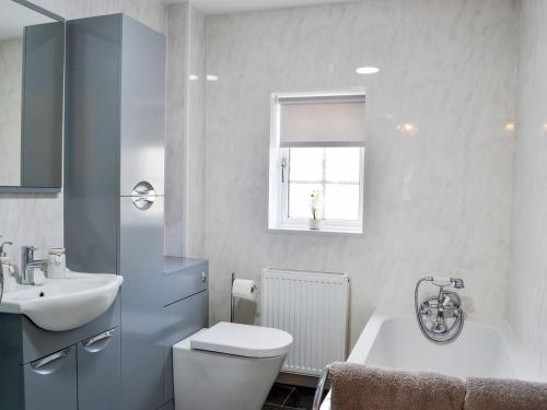 uma casa de banho com um WC, um lavatório e uma banheira em The Paddock em Bodelwyddan