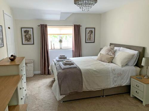 a bedroom with a large bed and a window at The Paddock in Bodelwyddan