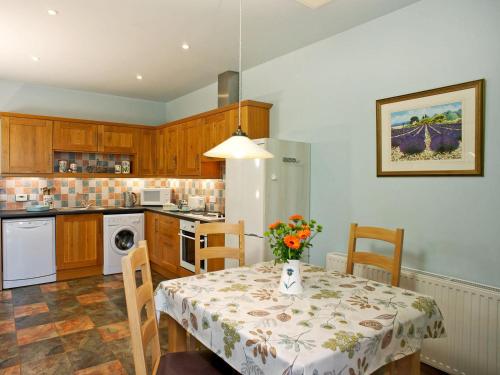 a kitchen with a table with a vase of flowers on it at The Bothy in Haywood