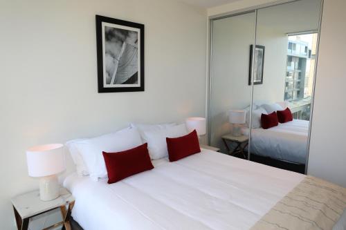 um quarto com uma grande cama branca com almofadas vermelhas em Realm Apartments by CLLIX em Adelaide