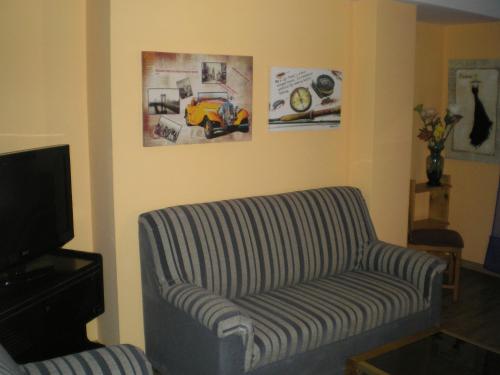 a living room with a striped couch and a tv at Apartamentos Augusta Centro in Zaragoza