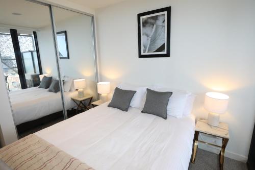 a bedroom with a large white bed with mirrors at Realm Apartments by CLLIX in Adelaide
