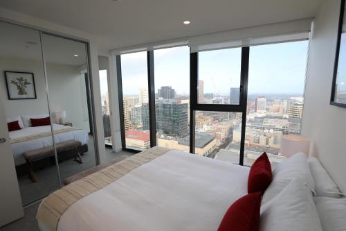 a bedroom with a large white bed and large windows at Realm Apartments by CLLIX in Adelaide