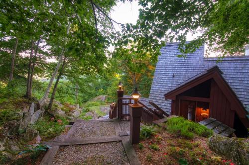 una casa en el bosque con un camino que conduce a ella en Gnome Home Mountain Ski Chalet w/Sauna Killington, en Stockbridge