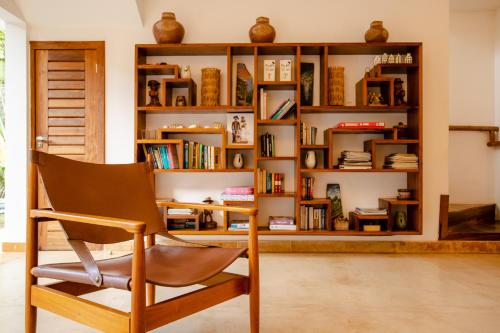 a chair in front of a book shelf with books at VillaMag in Jericoacoara