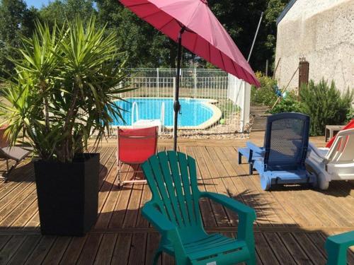 - un groupe de chaises et un parasol à côté de la piscine dans l'établissement Grand gîte avec piscine, cheminée et terrasse près de Lunéville, idéal pour familles et groupes - FR-1-584-84, à Athienville