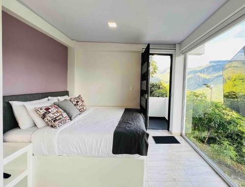 a bedroom with a bed and a large window at La Vista EcoHouse in Macanal