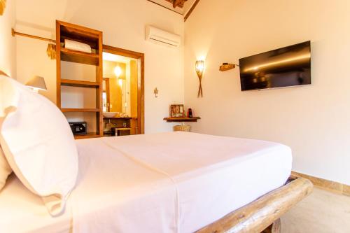a bedroom with a white bed and a tv on the wall at VillaMag in Jericoacoara