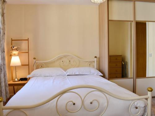 a bedroom with a large white bed and a mirror at Rosebank Cottage in Aldbrough