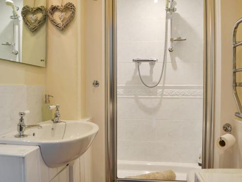 baño blanco con ducha y lavamanos en Garth Cottage, en Near Sawrey