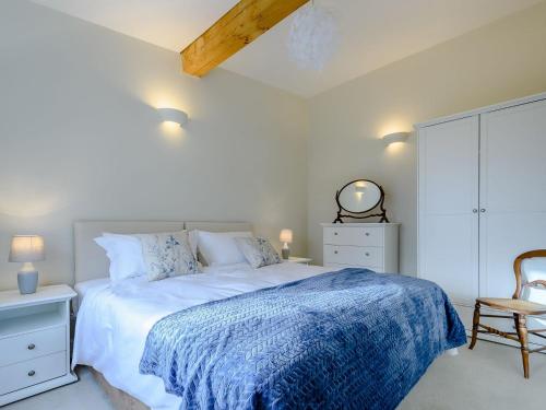 a white bedroom with a bed and a chair at Coach House Cottage in Wotton-under-Edge