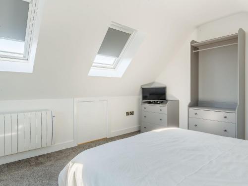 a white bedroom with a white bed and windows at Blackberry Cottage in Stowmarket