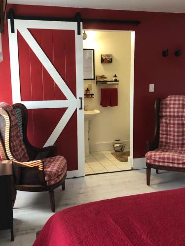 a bedroom with a sliding barn door and two chairs at The FarmHouse Inn Bed and Breakfast in Nappanee