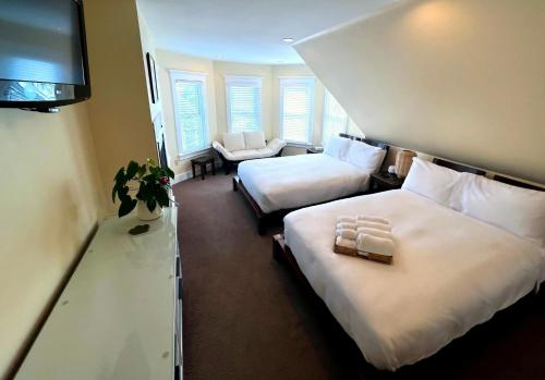 a hotel room with two beds and a flat screen tv at Lotus Provincetown in Provincetown