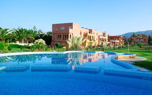 a large blue swimming pool with buildings in the background at Orpheas Resort Hotel (Adults Only) in Georgioupolis