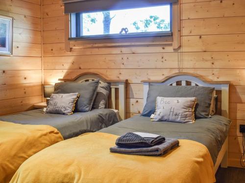 2 camas en una cabaña de madera con ventana en Oak Lodge - Uk30005, en Lindal in Furness