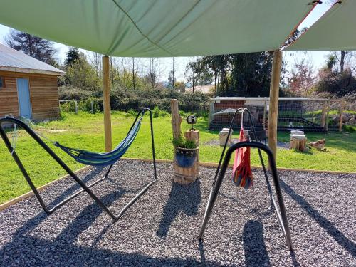 a couple of swings in a yard with an umbrella at Cabañas El Desván in Puente Negro