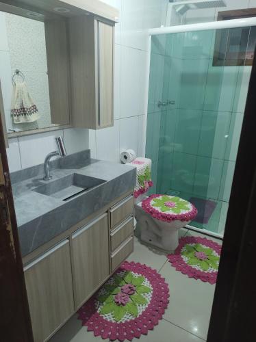 Un baño con lavabo e inodoro con flores en el suelo. en Casa no centro de Urubici Dutra Borba, en Urubici
