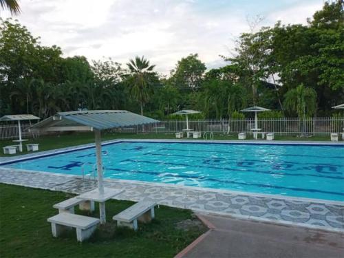 ein großer blauer Pool mit Bänken und Sonnenschirmen in der Unterkunft GRANJA CAMPESTRE EN CONDOMINIO EL GUAMO-TOLIMA in Guamo