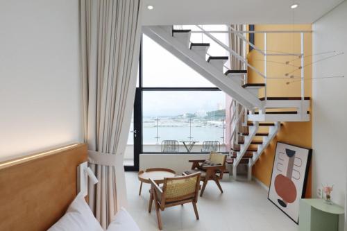 a room with a staircase and a table and chairs at Bau Haus in Sokcho