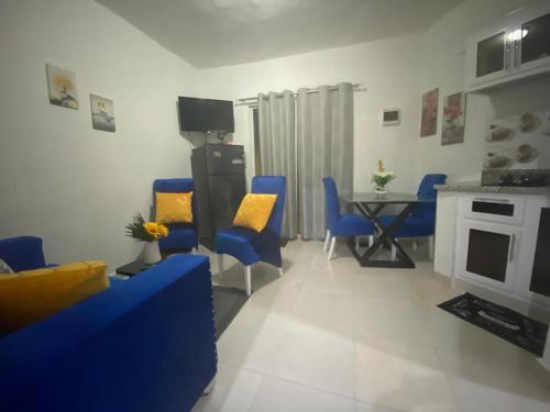 a living room with blue chairs and a table at Estancia Las Mercedes in San Felipe de Puerto Plata