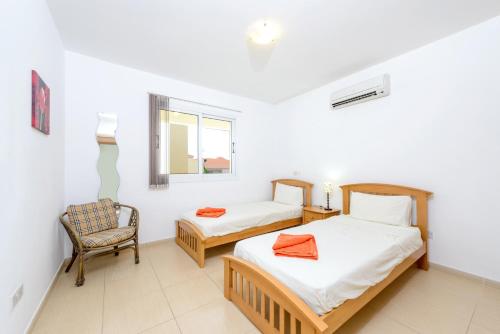 a bedroom with two beds and a chair and a window at Great Kings Resorts in Protaras