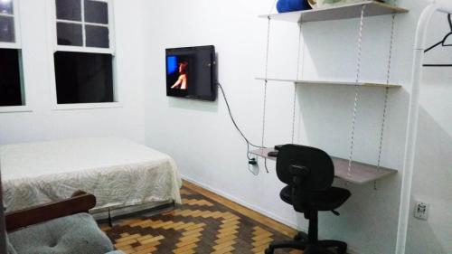 a bedroom with a bed and a chair and a tv at Sobrado Tranquilo Centro in Porto Alegre