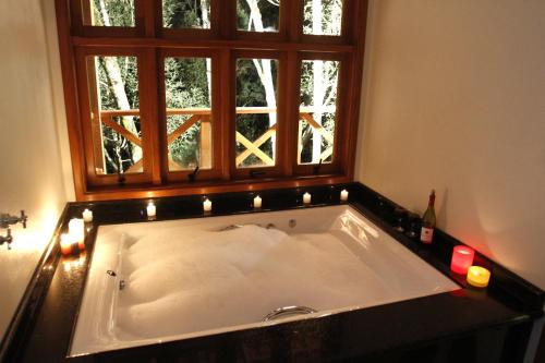 a bath tub in a bathroom with a window at Pousada Chalé da Floresta in Monte Verde