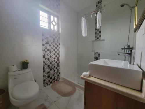 a white bathroom with a toilet and a sink at Estancia Las Mercedes in San Felipe de Puerto Plata