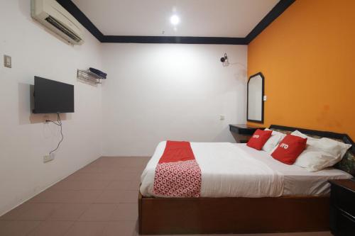 a bedroom with a bed with red pillows and a tv at G CITY HOTEL in Teluk Intan