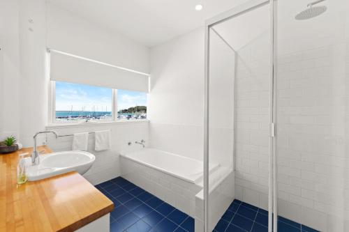 La salle de bains blanche est pourvue d'une baignoire et d'un lavabo. dans l'établissement Crows Nest 6 Teramby Road D Albora Marina, à Nelson Bay