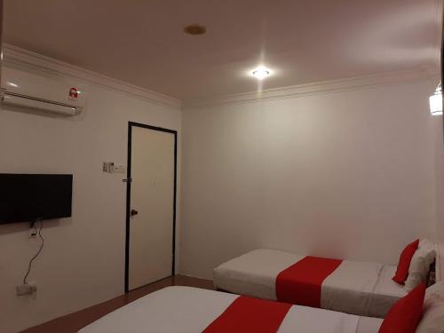 a bedroom with two beds and a flat screen tv at G CITY HOTEL in Teluk Intan