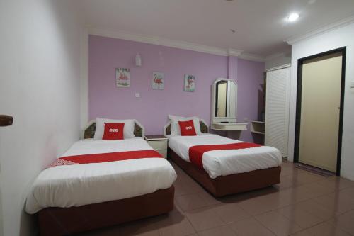 two beds in a room with purple walls at G CITY HOTEL in Teluk Intan