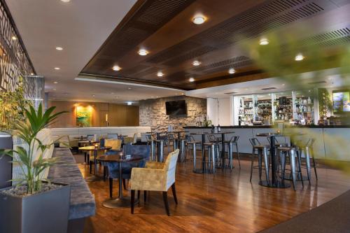 a restaurant with tables and chairs and a bar at Novotel Auckland Ellerslie in Auckland