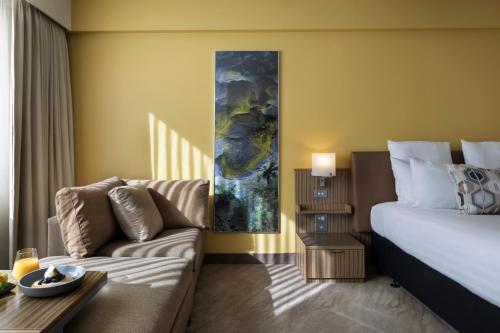 a hotel room with a bed and a couch at Novotel Auckland Ellerslie in Auckland