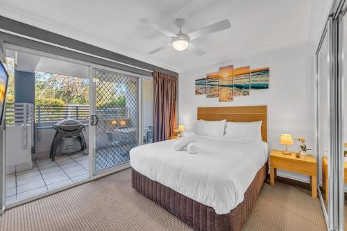 a bedroom with a large bed and a balcony at Shoal Bay Beach Apartments Unit 6 2 Shoal Bay Road in Shoal Bay