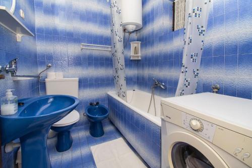 uma casa de banho azul com um lavatório e uma máquina de lavar roupa em Apartments Ivan em Srima