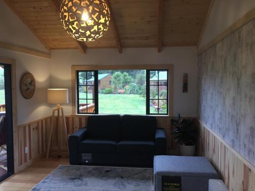 uma sala de estar com um sofá e uma grande janela em The River Lodge em Ohakune