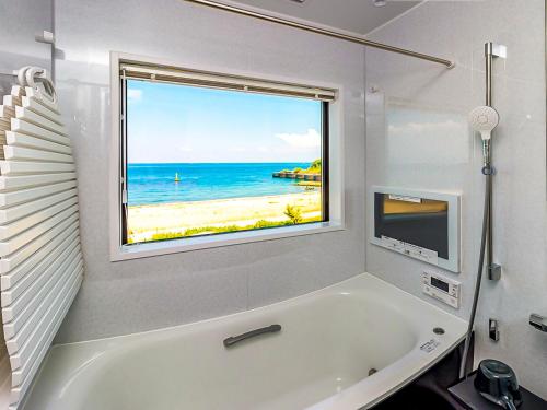 a bathroom with a tub and a window with a beach at T.Square in Akashi
