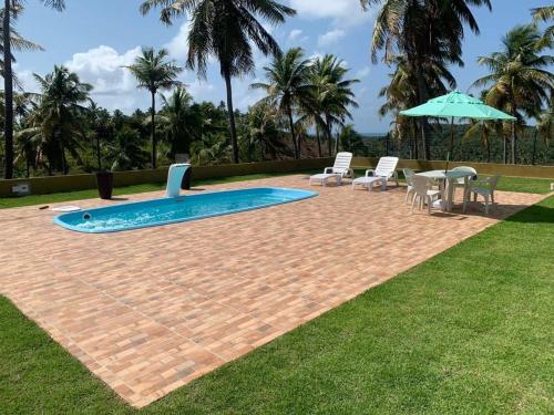 een zwembad met stoelen, een tafel en een parasol bij Casa Paraíso de Maragogi -condomínio fechado in Maragogi