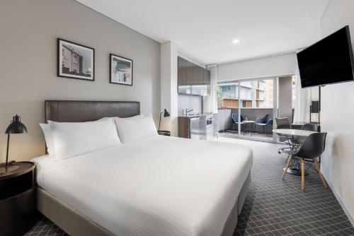 a bedroom with a large white bed and a living room at Holiday Inn & Suites Sydney Bondi Junction, an IHG Hotel in Sydney