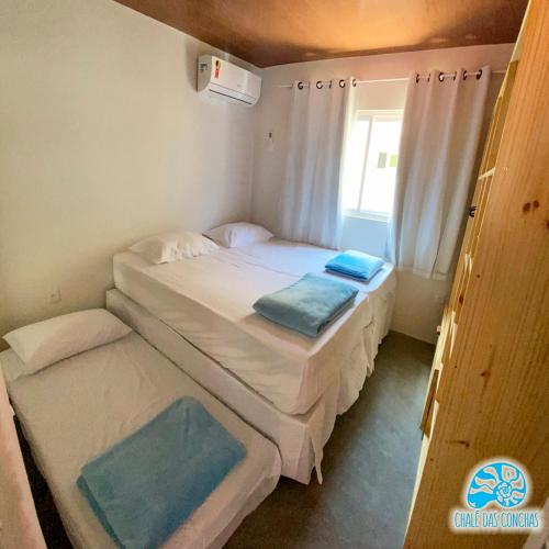 2 Betten in einem kleinen Zimmer mit Fenster in der Unterkunft Chalé das Conchas in Pipa