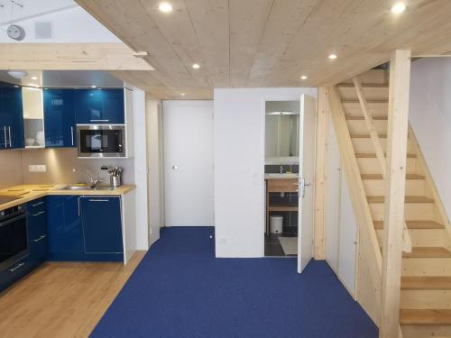 une cuisine avec des armoires bleues et un escalier dans l'établissement Appartement rénové · Ski aux pieds · Balcon · Wifi - FR-1-346-492, à Arc 1800