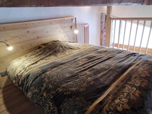 Ce lit se trouve dans une chambre dotée d'un mur en bois. dans l'établissement Appartement rénové · Ski aux pieds · Balcon · Wifi - FR-1-346-492, à Arc 1800