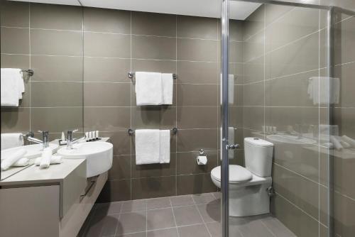 a bathroom with two sinks a toilet and a shower at Holiday Inn & Suites Sydney Bondi Junction, an IHG Hotel in Sydney