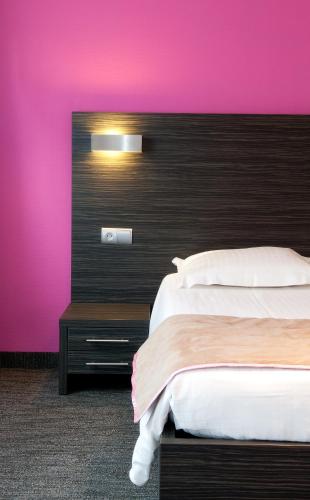a bedroom with a bed and a pink wall at Ostend Hotel in Ostend