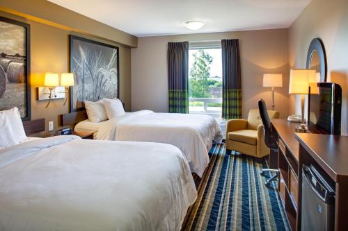 a hotel room with two beds and a television at Super 8 by Wyndham Brandon MB in Brandon
