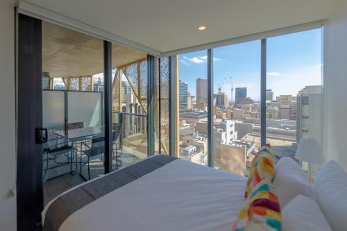 a bedroom with a bed and a view of a city at Realm Apartments by CLLIX in Adelaide