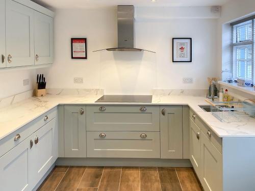 a large kitchen with white cabinets and a sink at The White Cottage in Gargrave