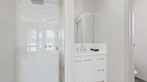 a white bathroom with a shower and a sink at Pelican House in Lakes Entrance